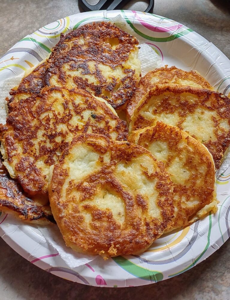 Crispy, golden-brown mashed potato cakes on a paper plate, pan-fried and ready to serve.